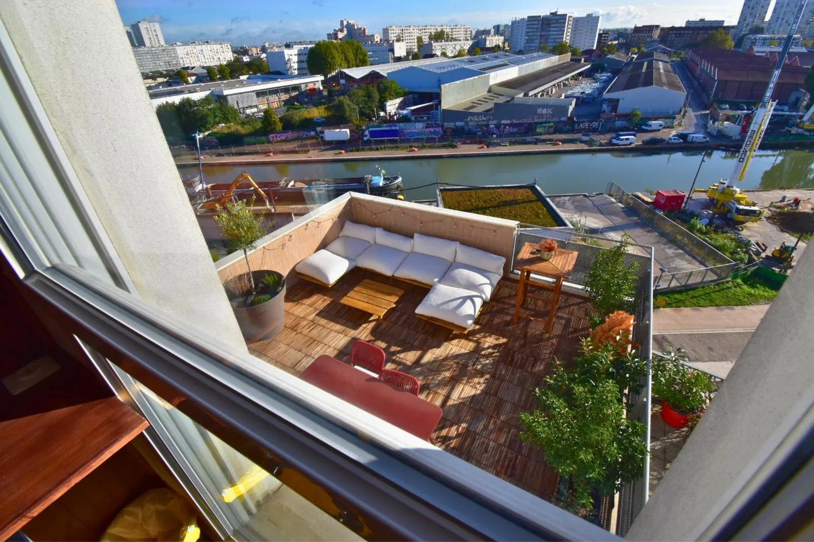 Terrasse après : deck en bois ipe, salon de jardin blanc, vue sur le canal d'Aubervilliers