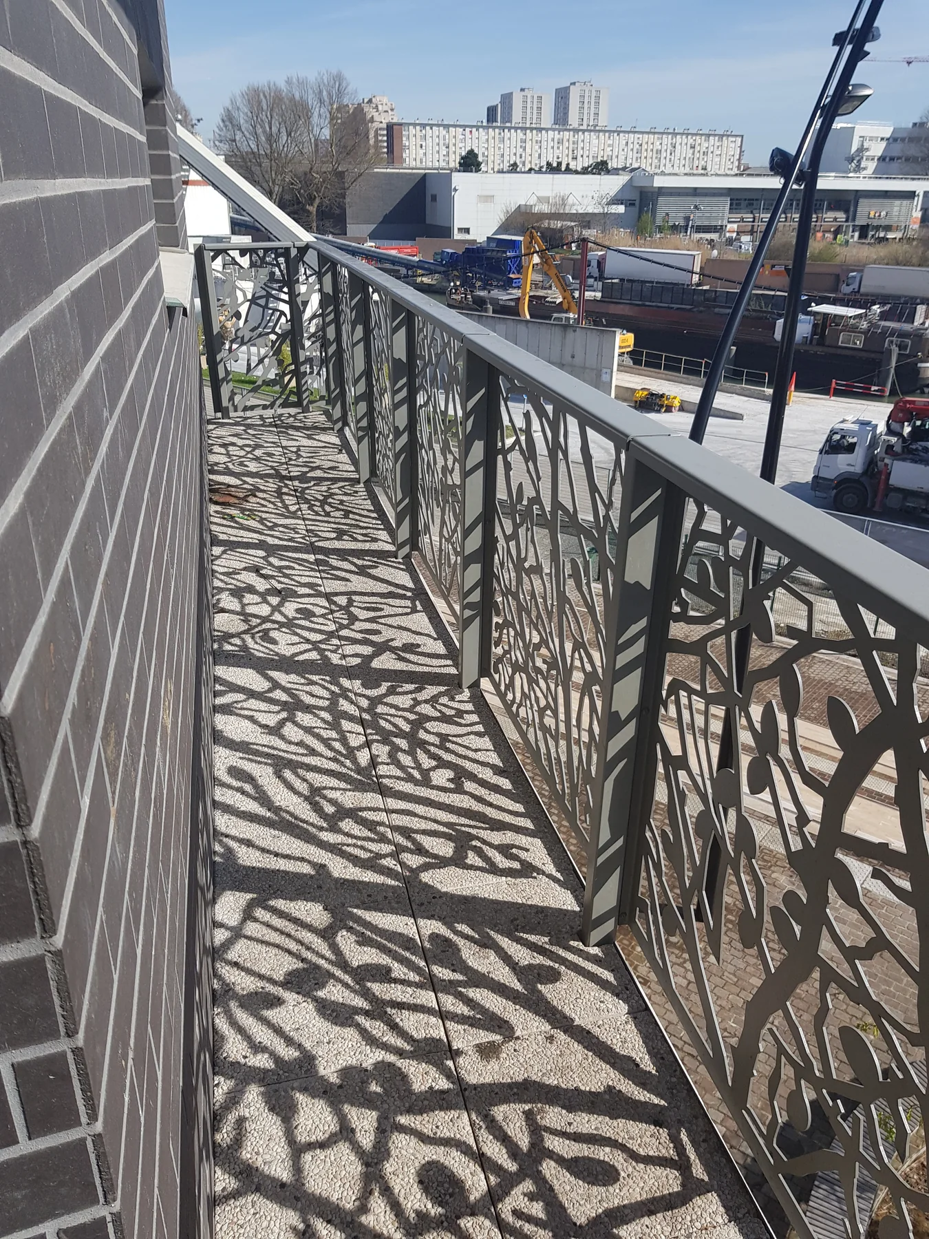 Balcon avant intervention : garde-corps, vue urbaine, aucun aménagement
